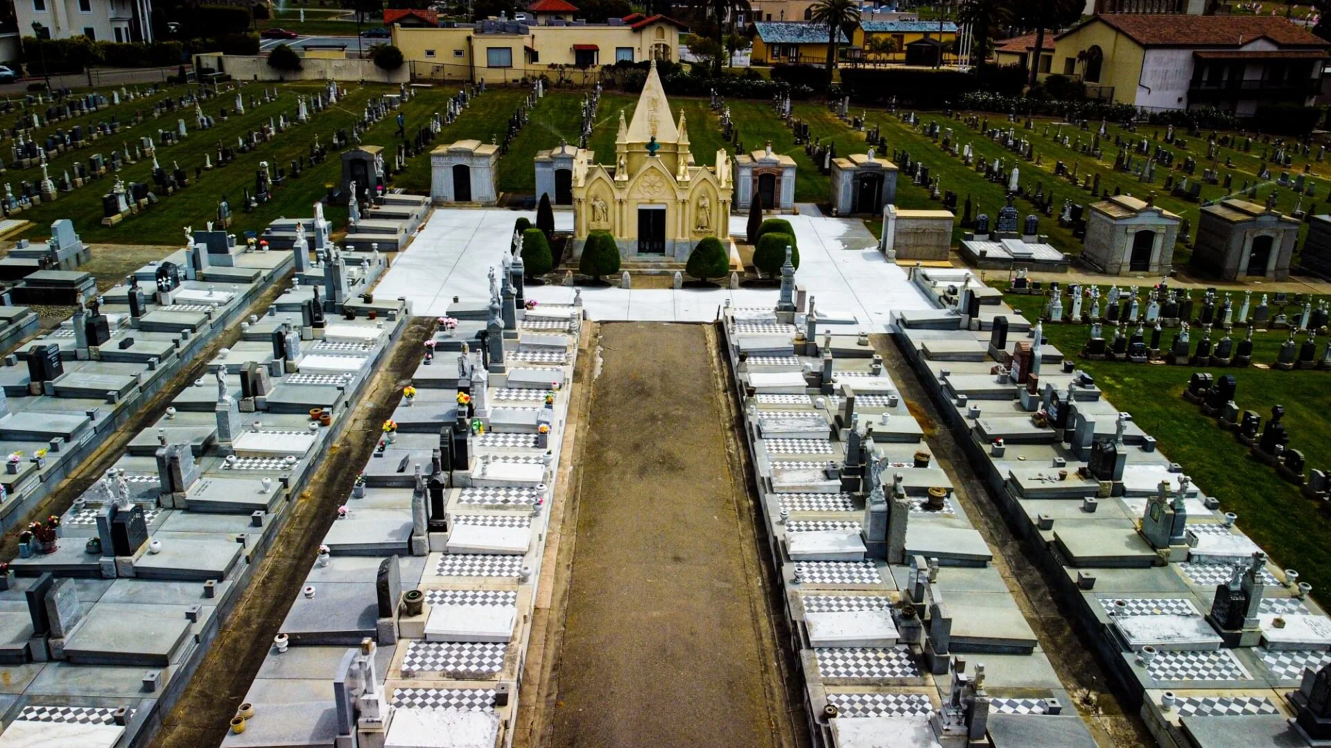 Aerial view of the cemetery grounds centered around a small chapel with a pointed steeple.