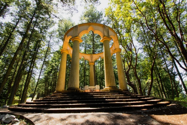 A circle of columns at the top of a platform in a wooded grove