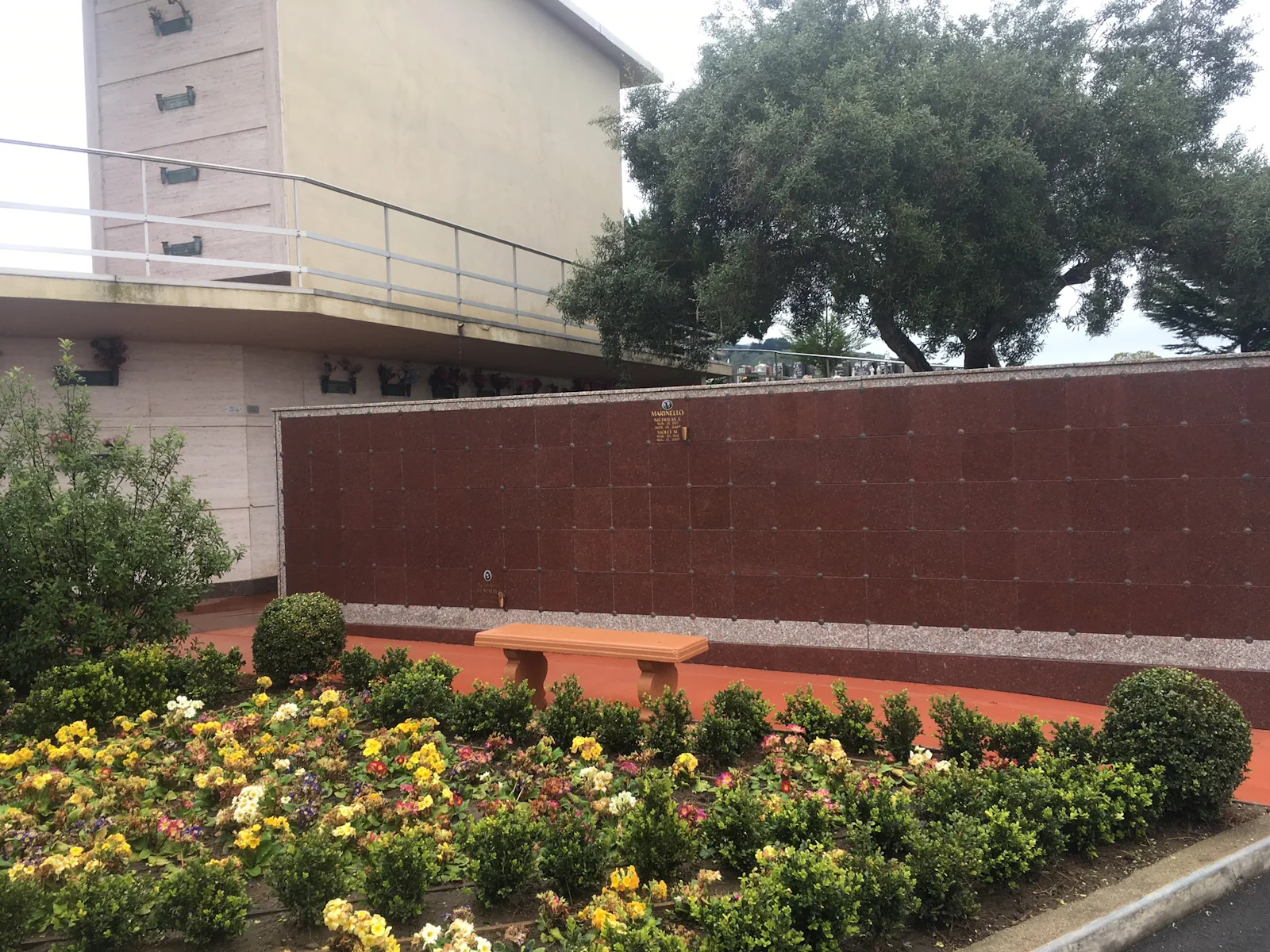 granite-columbarium-wall outdoor mausoleum wall behind a flower bed planted with colorful primroses