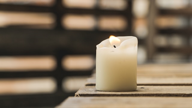 Lit remembrance candle placed on a grave in a peaceful cemetery setting.