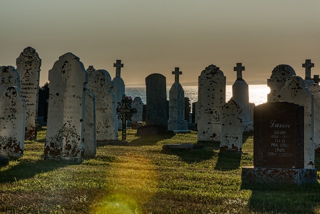 Sunlit cemetery with weathered headstones and crosses silhouetted against the horizon, South San Francisco, CA.