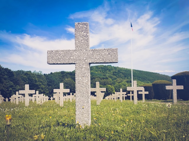 White cross headstones in a peaceful cemetery beneath a blue sky, with green hills in the background, San Mateo, CA.